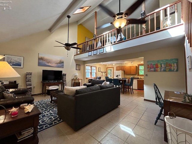 living room with beam ceiling, plenty of natural light, ceiling fan, and light tile floors