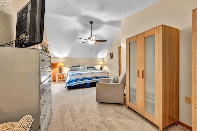 bedroom with ceiling fan, vaulted ceiling, a textured ceiling, and light carpet