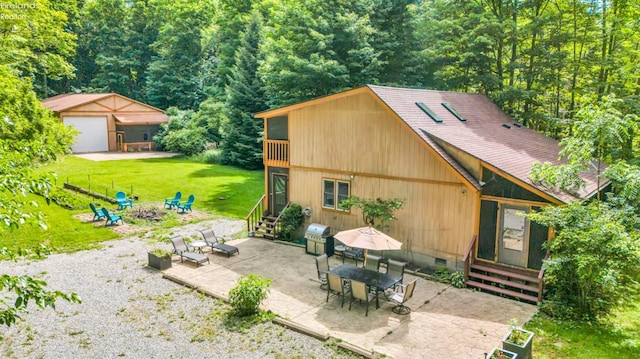 exterior space featuring an outdoor structure, a garage, a yard, a patio area, and a fire pit