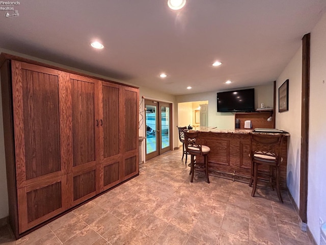 kitchen featuring a breakfast bar, tile floors, and light stone counters