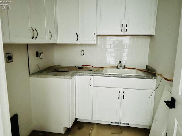 kitchen featuring visible vents, decorative backsplash, white cabinets, and a sink