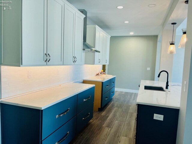 kitchen with dark wood-style floors, backsplash, white cabinetry, a sink, and blue cabinets