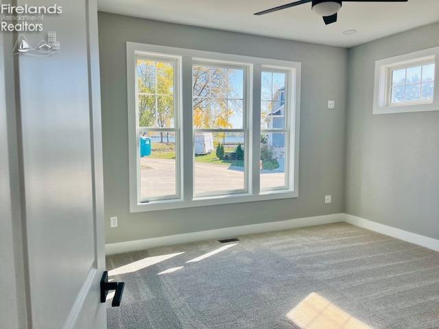 empty room with baseboards, carpet, visible vents, and a healthy amount of sunlight