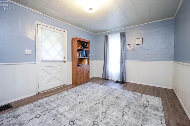 foyer featuring wood-type flooring and crown molding