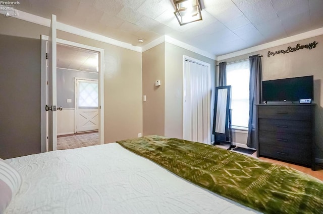 bedroom with multiple windows, a closet, and ornamental molding