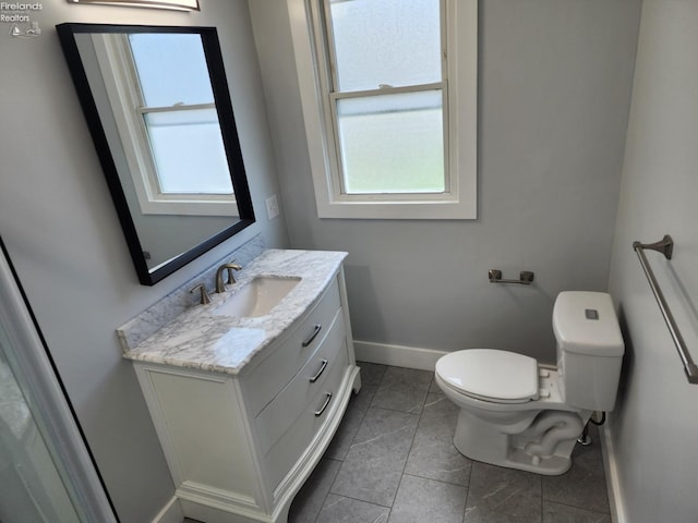 bathroom with toilet, vanity, tile patterned flooring, and plenty of natural light