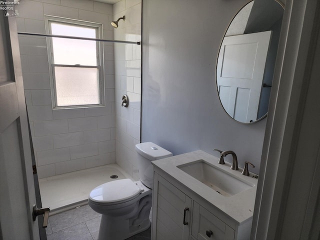 bathroom with toilet, tile patterned flooring, a tile shower, and vanity