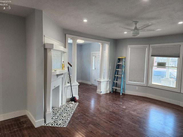 living room featuring ceiling fan, a textured ceiling, dark hardwood / wood-style floors, and ornate columns