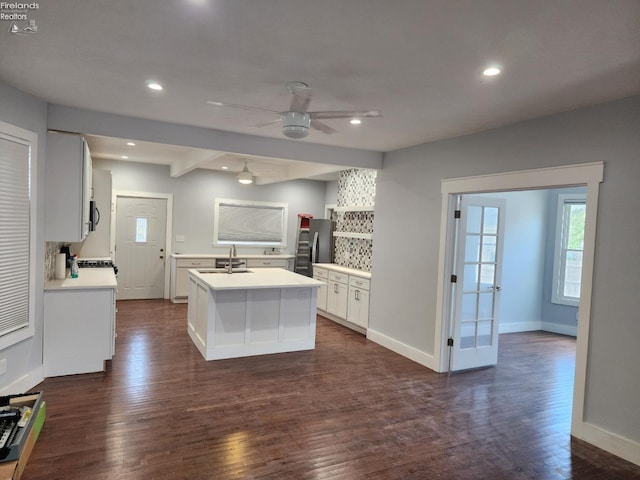 kitchen featuring dark wood-type flooring, stainless steel appliances, a kitchen island with sink, white cabinetry, and sink