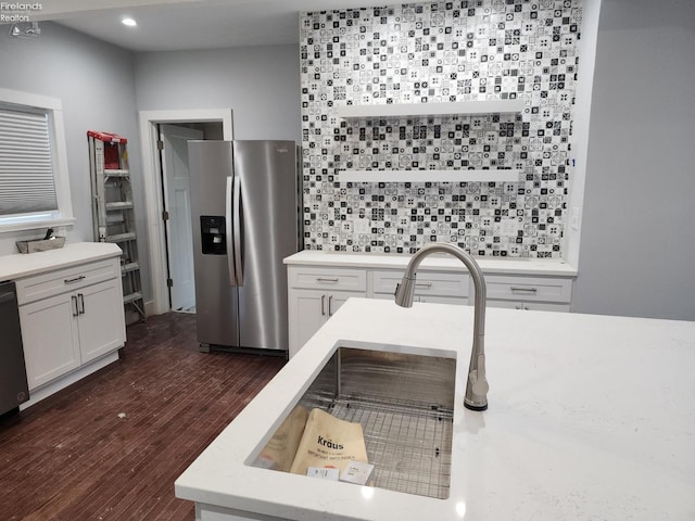 kitchen featuring dark wood-type flooring, stainless steel refrigerator with ice dispenser, black dishwasher, white cabinetry, and backsplash