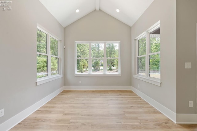 unfurnished room featuring lofted ceiling and light wood-type flooring