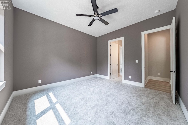 unfurnished bedroom with a textured ceiling, light colored carpet, and ceiling fan