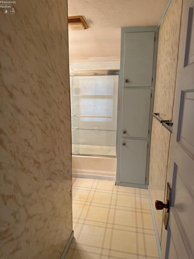 bathroom with shower / bath combination, tile patterned floors, and a textured ceiling