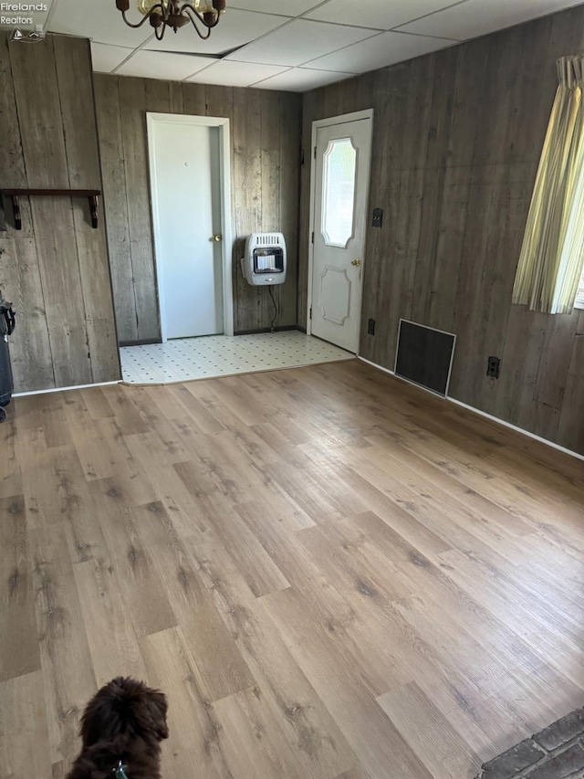 unfurnished living room featuring wooden walls, light hardwood / wood-style flooring, and a paneled ceiling