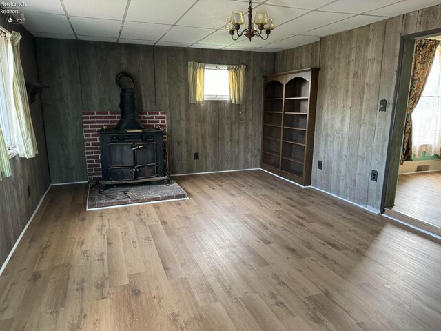 1225 White Ave, Fremont, OH 43420 - unfurnished living room with a chandelier, a drop ceiling, wood finished floors, and a wood stove