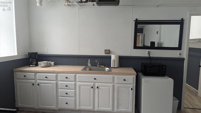 kitchen featuring white cabinets, washer / clothes dryer, hardwood / wood-style floors, and sink