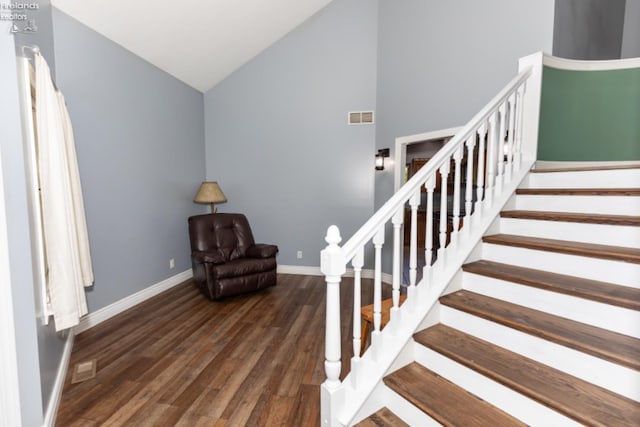 staircase featuring wood-type flooring and high vaulted ceiling