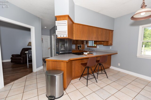 kitchen with light hardwood / wood-style flooring, sink, fridge with ice dispenser, kitchen peninsula, and a kitchen breakfast bar