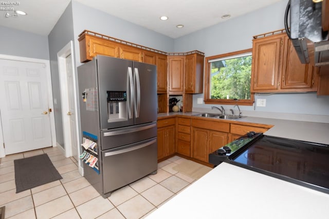 kitchen featuring sink, light tile patterned floors, stainless steel fridge, and electric stove