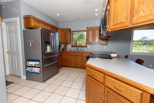 kitchen featuring plenty of natural light, light tile patterned floors, and stainless steel refrigerator with ice dispenser