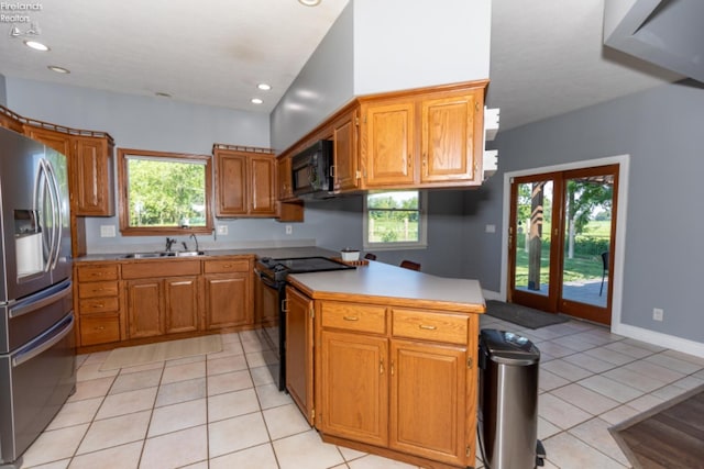 kitchen with sink, kitchen peninsula, light tile patterned floors, and black appliances