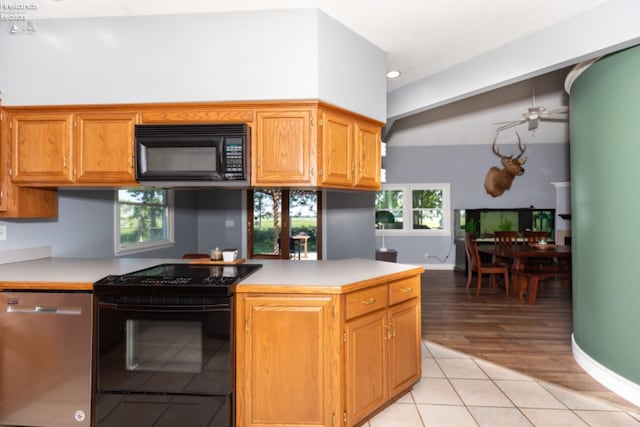 kitchen featuring ceiling fan, kitchen peninsula, light tile patterned floors, and black appliances