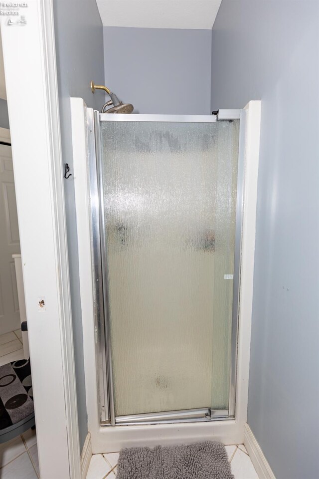 bathroom with a shower with door and tile patterned floors