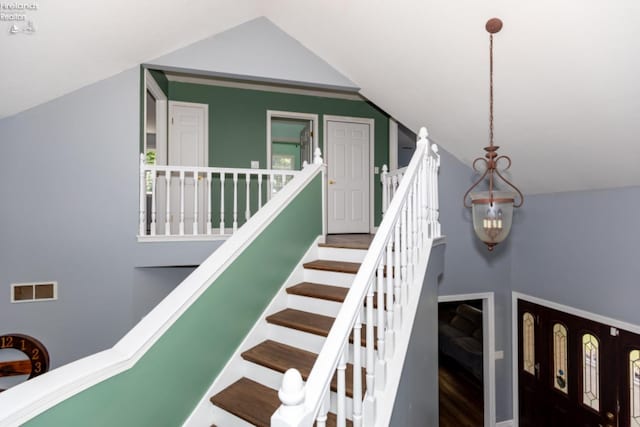 stairs featuring high vaulted ceiling and wood-type flooring