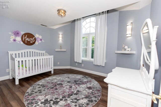 bedroom featuring a crib and dark hardwood / wood-style floors