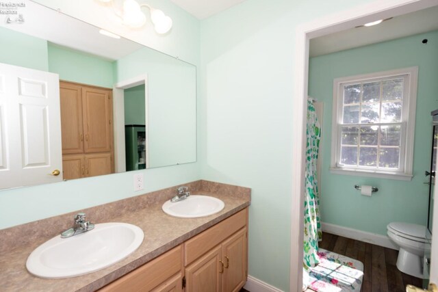 bathroom featuring hardwood / wood-style floors, double vanity, and toilet