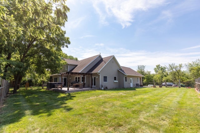 rear view of property with a lawn, a hot tub, and a patio area