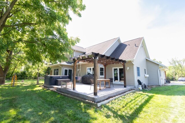 back of house with a hot tub, a patio area, a yard, and a pergola