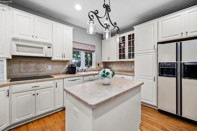 kitchen with light hardwood / wood-style flooring, tasteful backsplash, white appliances, white cabinets, and a center island