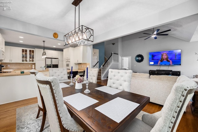 dining area featuring ceiling fan with notable chandelier, dark hardwood / wood-style flooring, and lofted ceiling