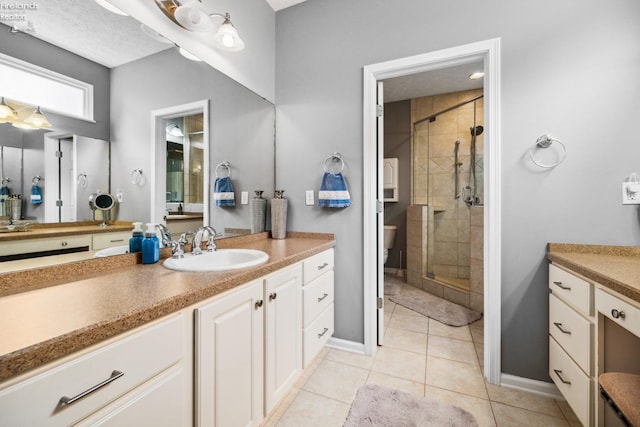 bathroom with tile patterned floors, vanity, a shower with door, and toilet