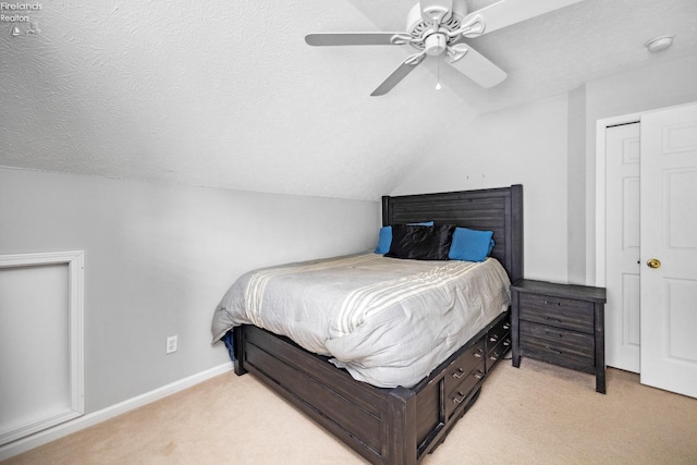 carpeted bedroom with lofted ceiling, a textured ceiling, a closet, and ceiling fan