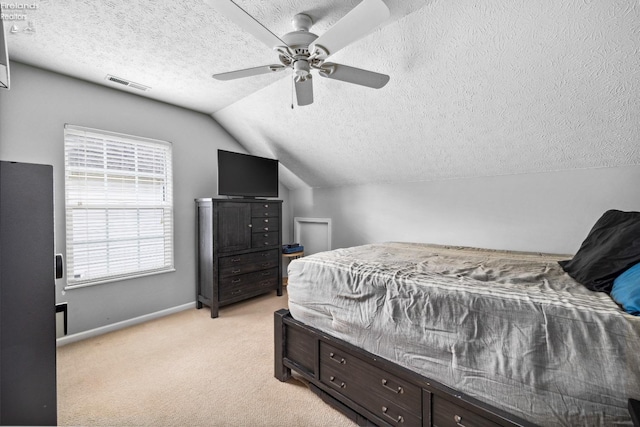 bedroom featuring ceiling fan, light carpet, vaulted ceiling, and a textured ceiling