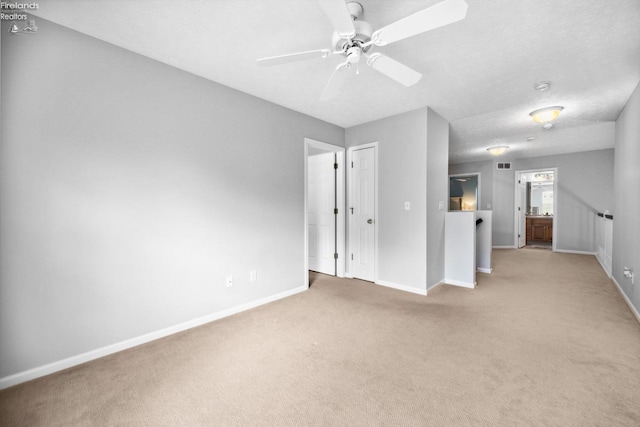 unfurnished room featuring a textured ceiling, ceiling fan, and light colored carpet