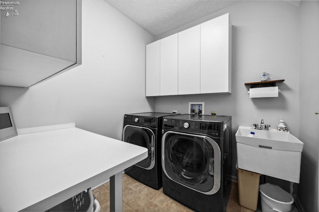 laundry area featuring light tile patterned floors, a textured ceiling, independent washer and dryer, cabinets, and sink