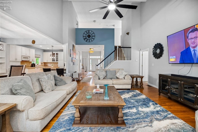 living room featuring ceiling fan, wood-type flooring, and a high ceiling