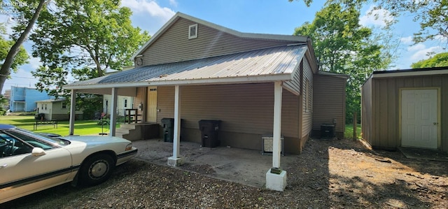 view of side of property with central AC unit, a porch, and a storage unit