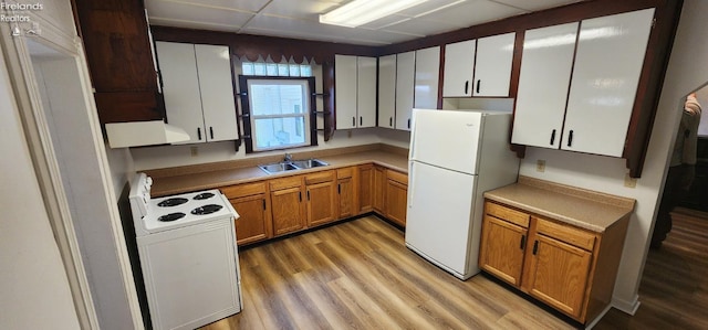 kitchen with white cabinets, light hardwood / wood-style flooring, sink, and white appliances