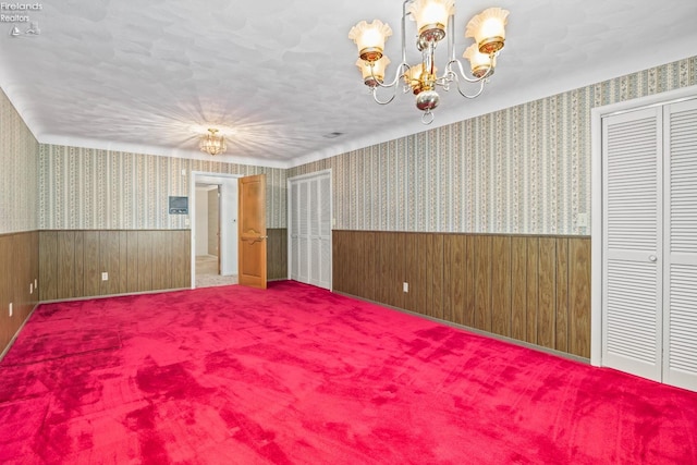 spare room with a notable chandelier and carpet