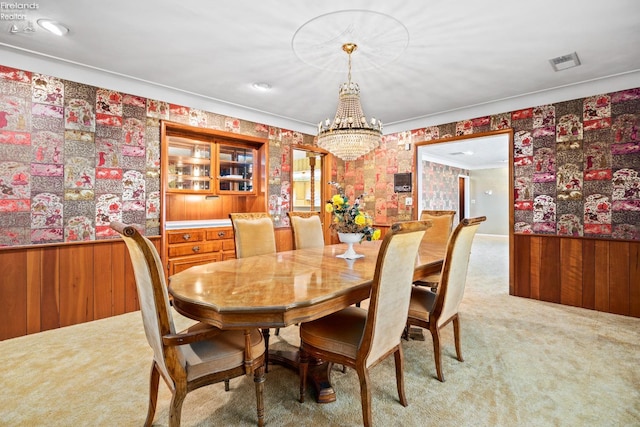 carpeted dining space with an inviting chandelier and ornamental molding