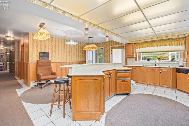 kitchen with a breakfast bar, sink, pendant lighting, dishwashing machine, and light tile patterned floors