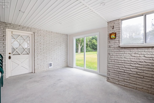 unfurnished room featuring concrete flooring and brick wall