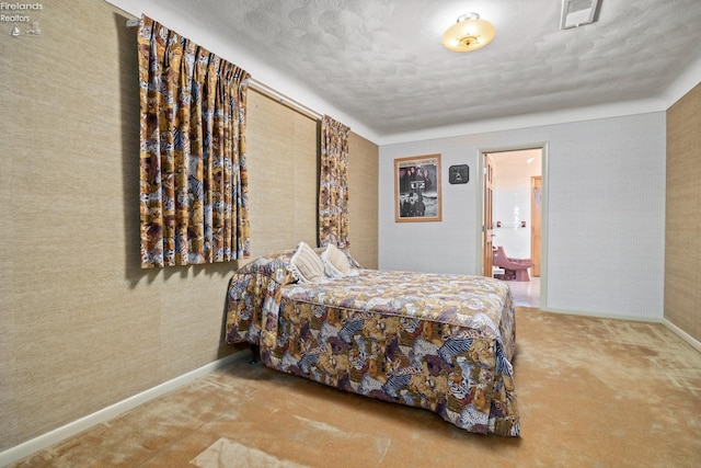 carpeted bedroom with ensuite bathroom and a textured ceiling