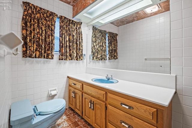 bathroom featuring tile patterned flooring, tile walls, toilet, and vanity