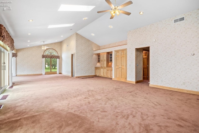 unfurnished living room with a skylight, light carpet, high vaulted ceiling, and ceiling fan