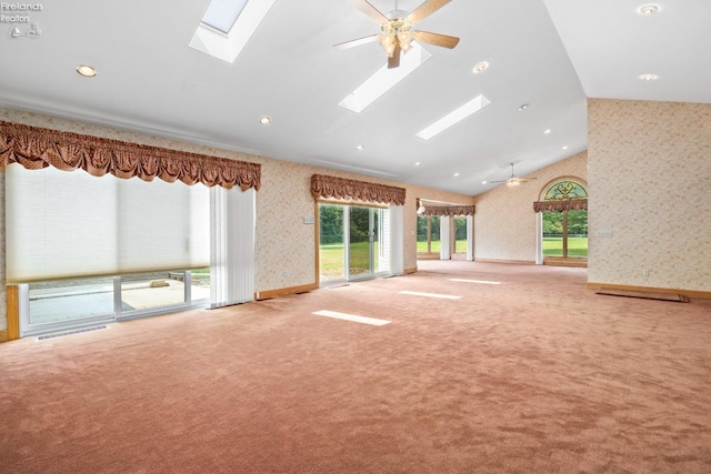 unfurnished living room with high vaulted ceiling, ceiling fan, a skylight, and light colored carpet